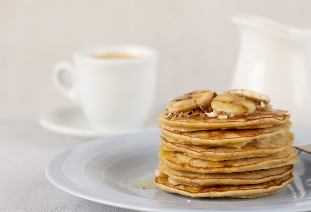 Pancakes on a plate with banana, honey, and nuts