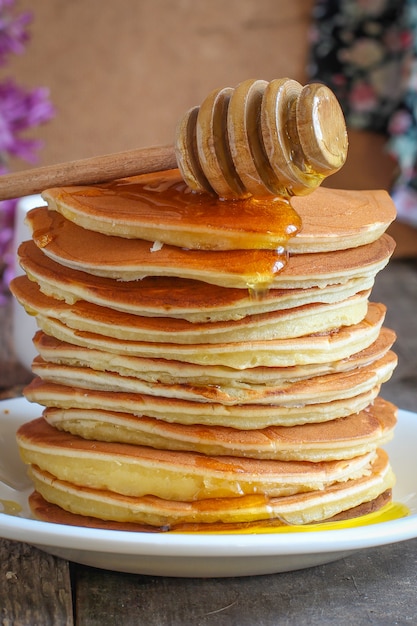 Pancakes in a plate on a wooden table with honey