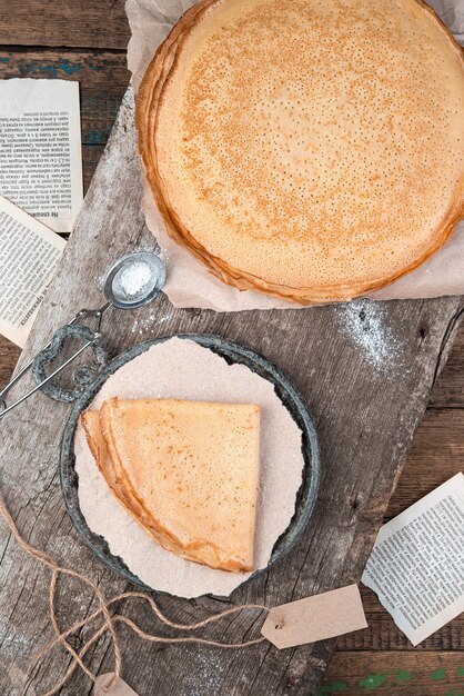 Pancakes sprinkled with powdered sugar on a vintage wooden background.