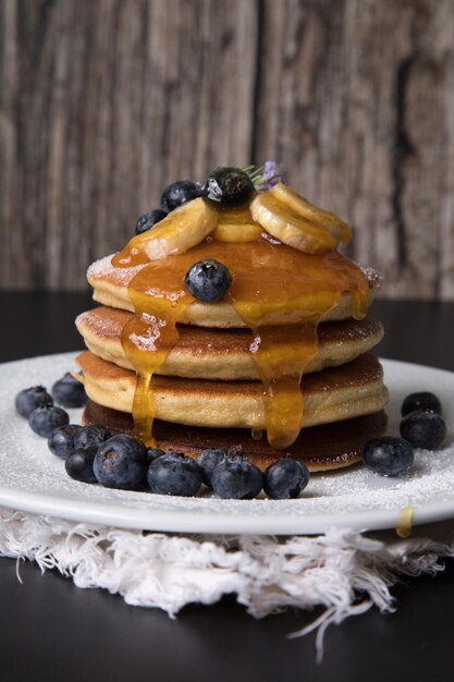 Pancakes stack with banana and blueberries topping and bee honey breakfast food