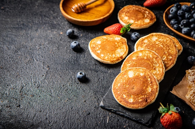 Pancakes on a stone board with fresh berries