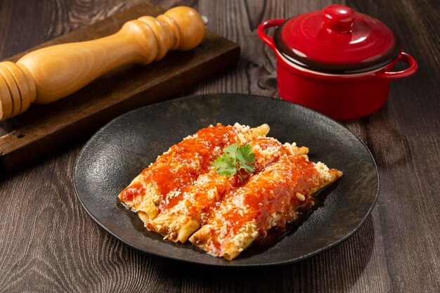 Pancakes stuffed with minced meat and topped with tomato sauce and grated cheese