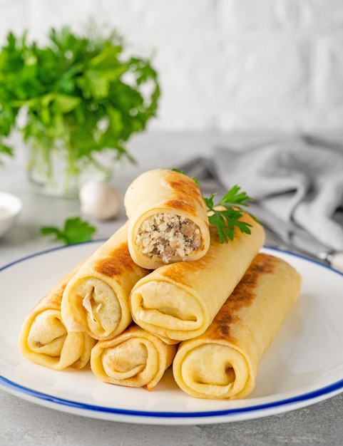 Pancakes or thin crepes stuffed with chicken and mushrooms on a plate Selective focus copy space