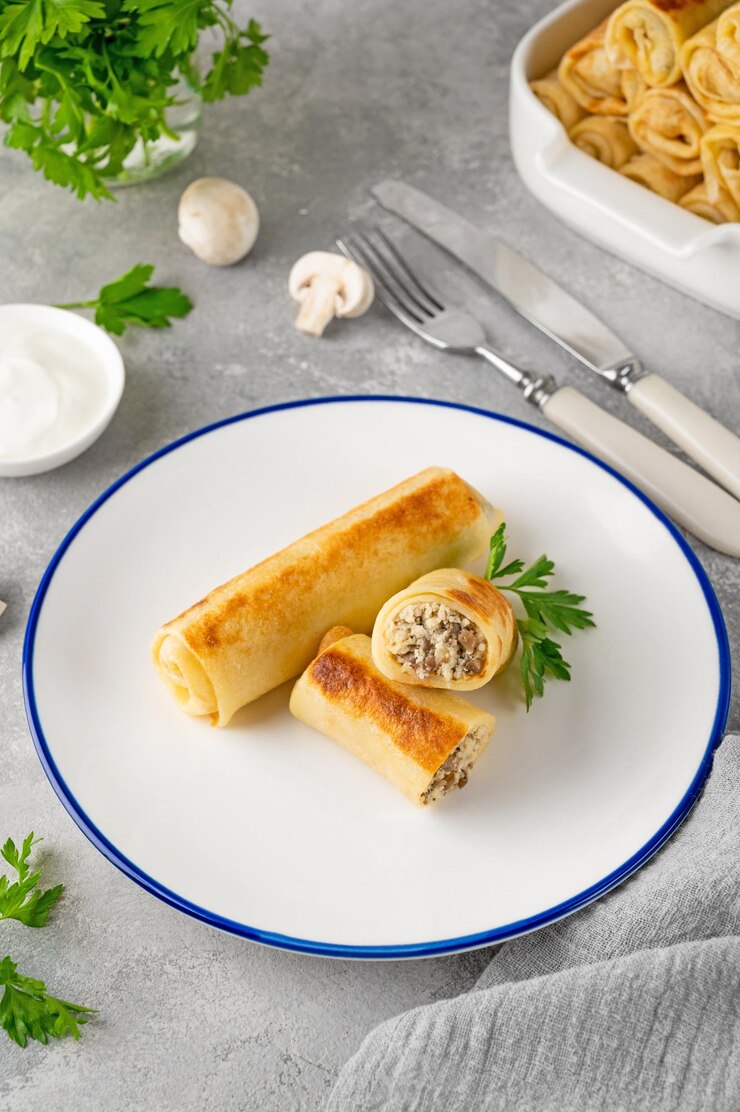 Блины или тонкие блинчики с начинкой из курицы и грибов на тарелке