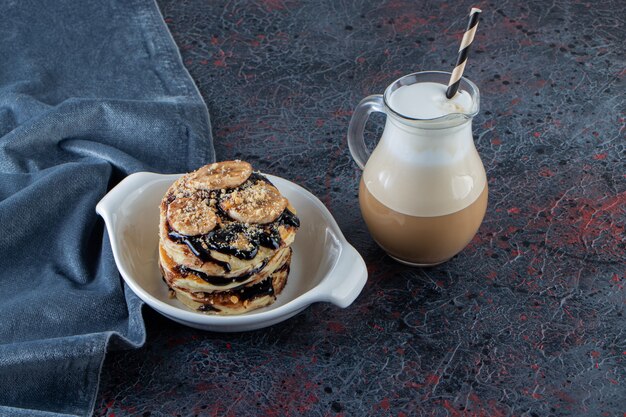 おいしいコーヒーと白いボウルにバナナとチョコレートのパンケーキ。