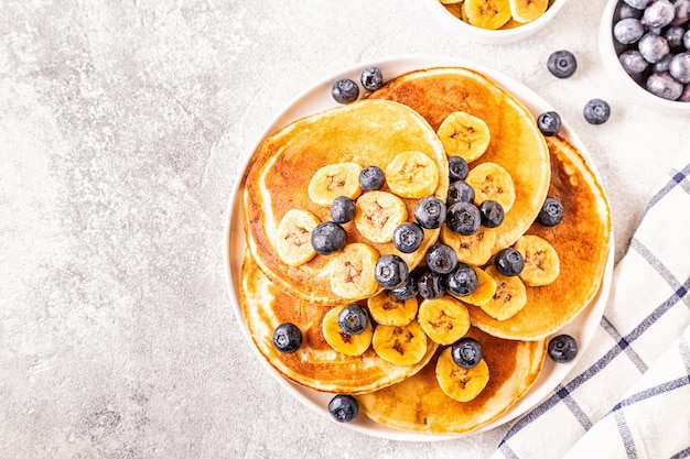 Pancakes with banana,  blueberries on white plate, selective focus.