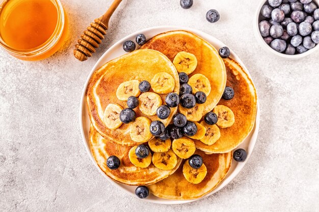 Pancakes with banana, blueberries on white plate, selective focus