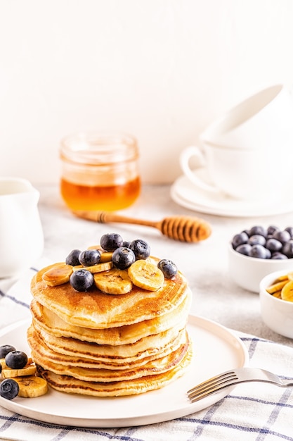 Pancakes with banana,  blueberries on white plate, selective focus.