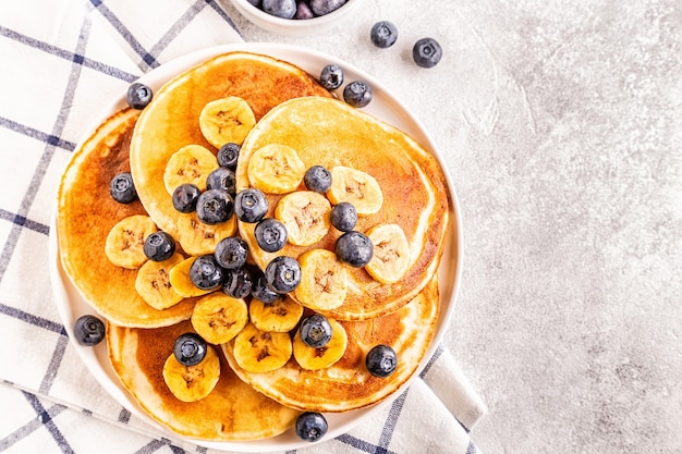 Pancakes with banana,  blueberries on white plate, selective focus.