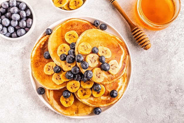 Pancakes with banana,  blueberries on white plate, selective focus.