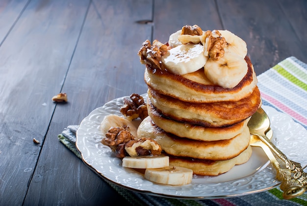 Pancakes with banana, nuts ,honey and cup coffee on dark