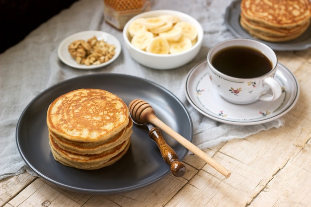 Pancakes with banana, nuts and honey, served with tea. Rustic style.