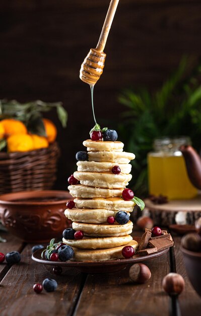 Pancakes with berries are stacked honey is poured on top