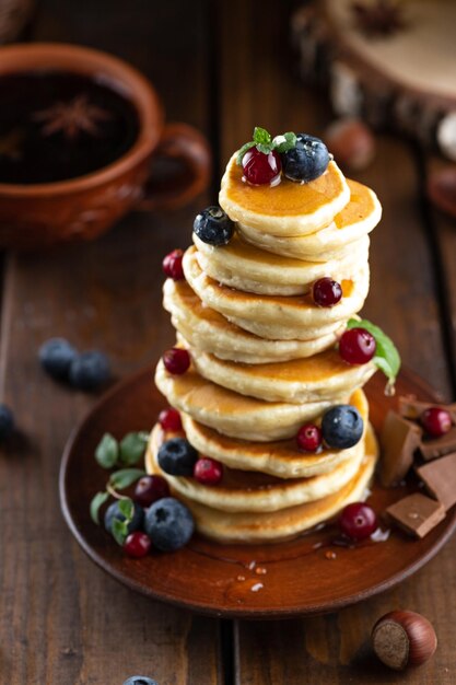 Pancakes with berries are stacked Pancakes poured with honey