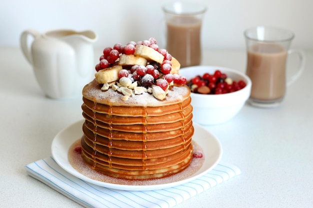 Pancakes with berries, banana and honey are sprinkled with powdered sugar