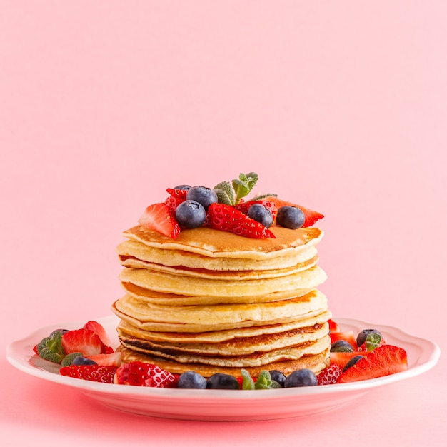 Pancakes with berries on a bright pastel background