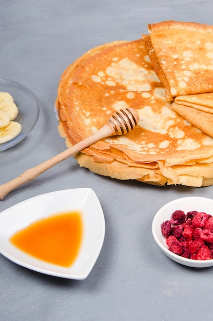 Pancakes with berries and honey for breakfast on white gray table