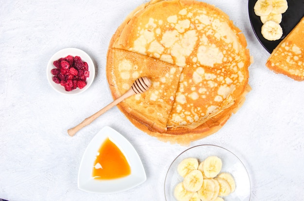 Pancakes with berries and honey for breakfast on white table