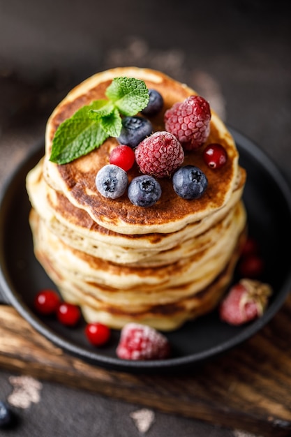 Pancakes with berries and maple syrup. Sweet homemade stack of pancakes