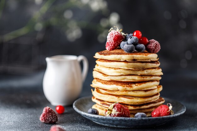 Pancakes with berries and maple syrup. Sweet homemade stack of pancakes