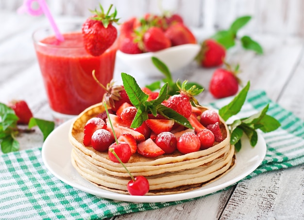 Pancakes with berries and strawberry smoothie in a rustic style