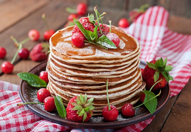 Pancakes with berries and syrup in a rustic style