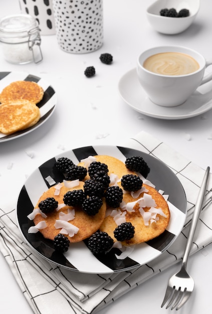 Pancakes with blackberries and coconut chips on white table. Homemade gluten free breakfast