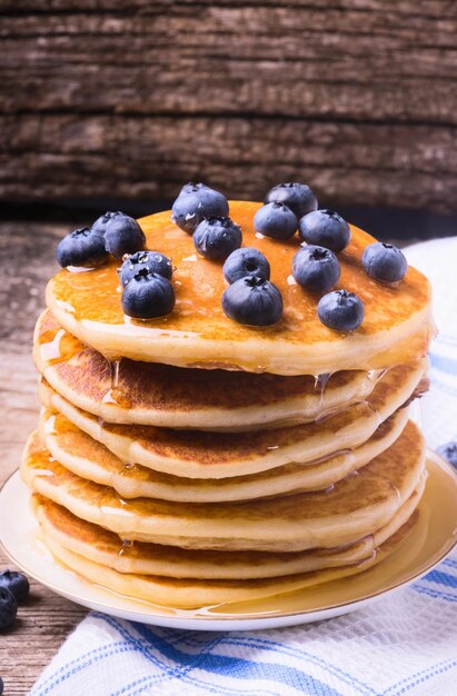 Pancakes with blueberries on wood background