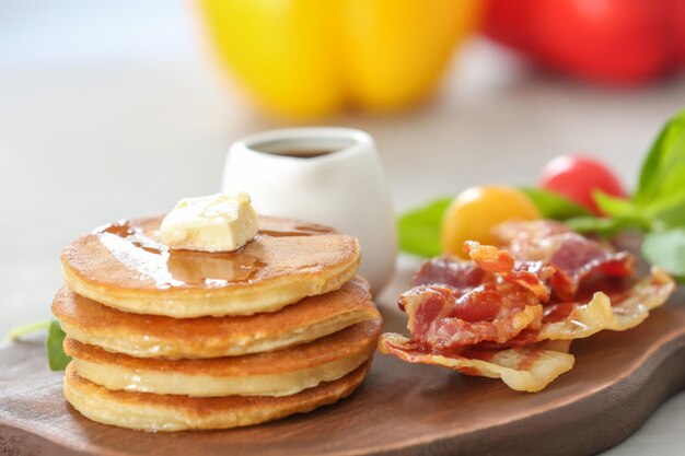 Pancakes with butter and bacon on wooden board