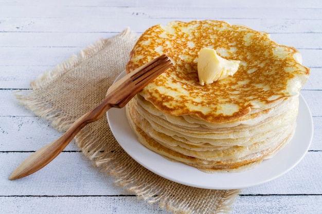 Pancakes with butter on a wooden background.