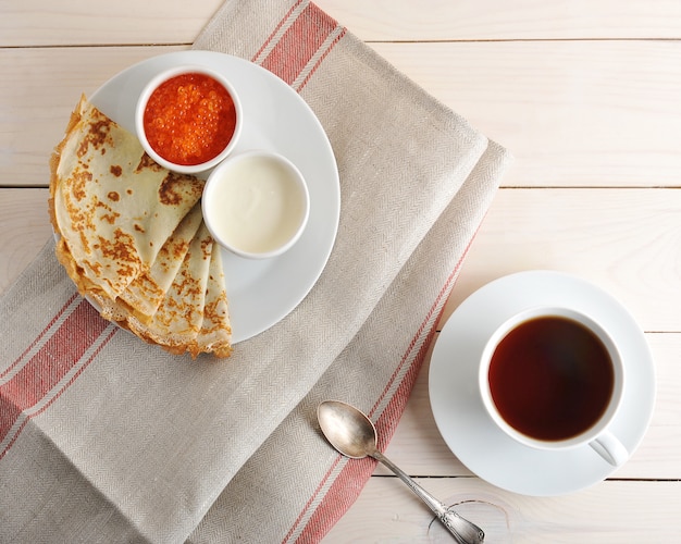 Pancakes with caviar and sour cream on a saucer 