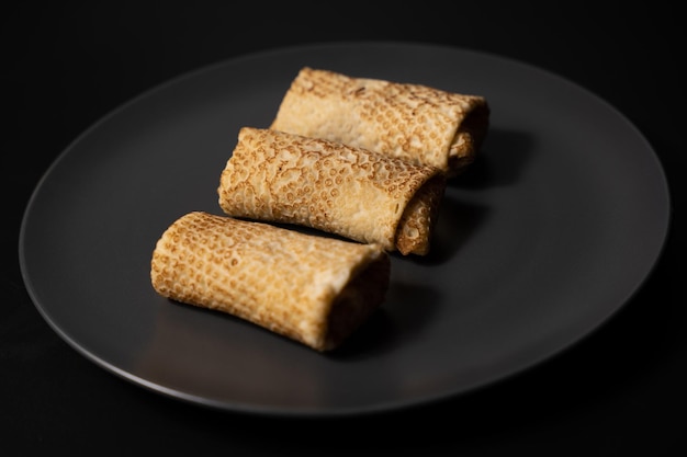 Pancakes with cheese on a plate and kitchen utensils on a black background