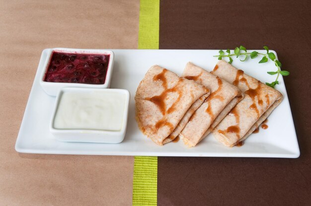 Pancakes with cherry jam on a white plate