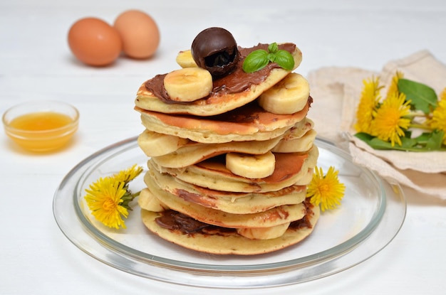 Pancakes with chocolate and banana and dandelion flowers