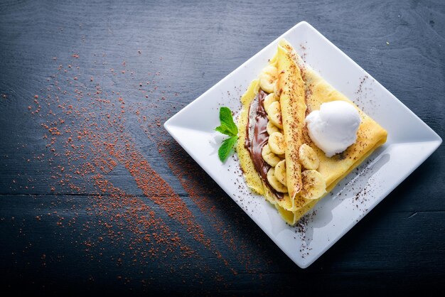 Pancakes with chocolate and banana. Dessert. On a wooden background. Top view. Free space for your text.