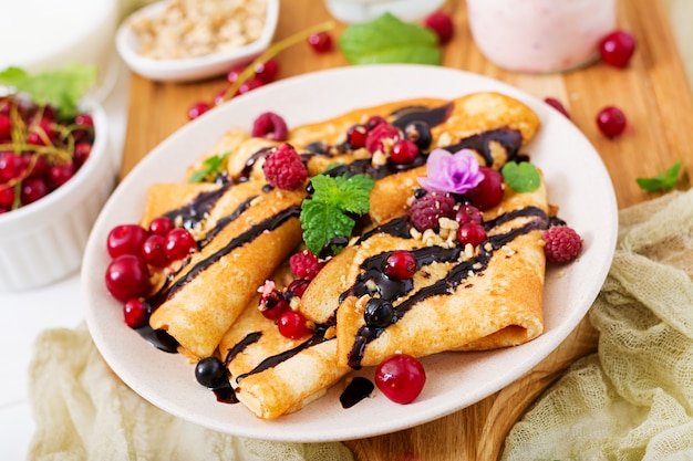 Pancakes with chocolate, honey, nuts and summer berries. Tasty breakfast