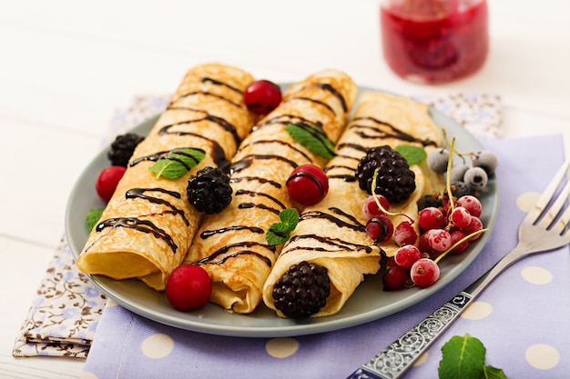 Pancakes with chocolate, jam and berries. Tasty breakfast.