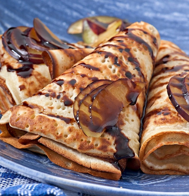 Pancakes with chocolate syrup and plums