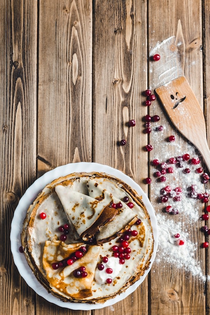 Pancakes with cranberries and sour cream on a wooden Board in flour