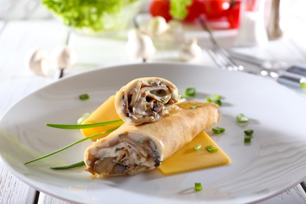 Pancakes with cream and mushrooms on wooden table closeup