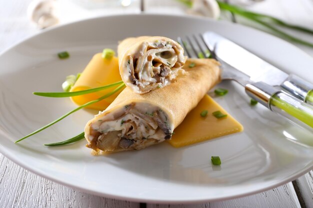 Pancakes with cream and mushrooms on wooden table closeup