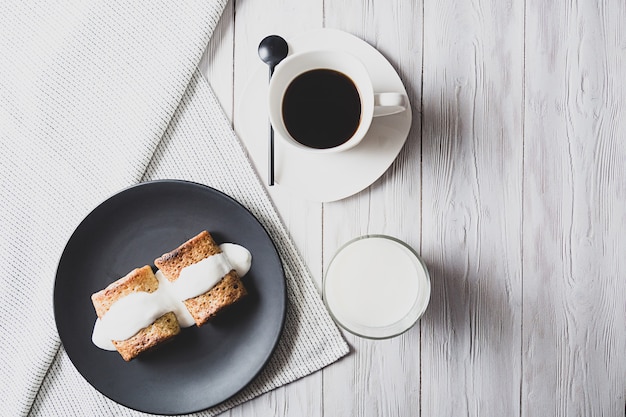 Pancakes with filling and sour cream, a glass of milk and a cup of black coffee