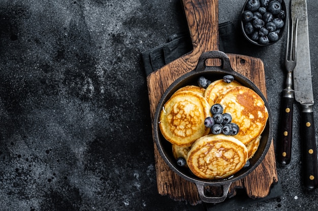 Pancakes with fresh blueberries and maple syrup in a pan.   Top View.