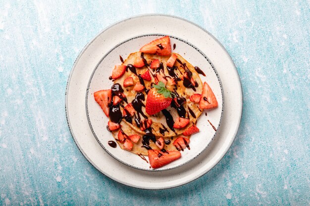 Pancakes with fresh strawberry on a blue wooden wall