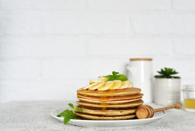 Frittelle con miele e banane per colazione sul tavolo della cucina.