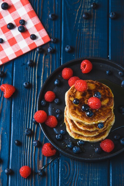 Pancakes with honey and berries on a wooden table