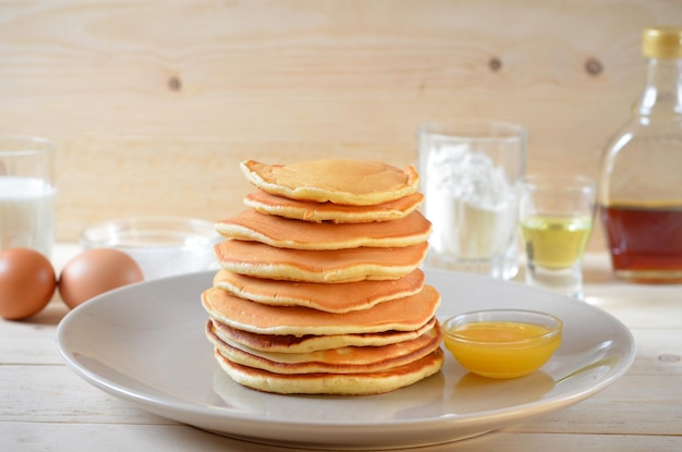 Pancakes with honey and ingredients for cooking on the table