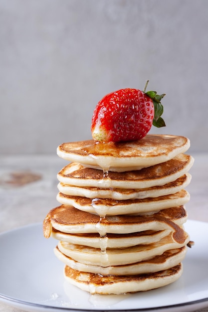 Pancakes with honey and strawberries lies on a plate