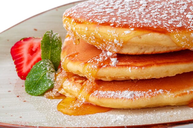 Pancakes with maple syrup on plate isolated on white