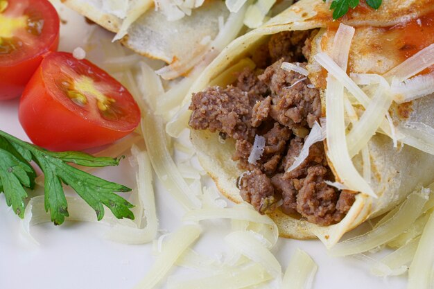 Pancakes with meat, in tomato sauce and cheese, with cilantro and grated cheese on top.